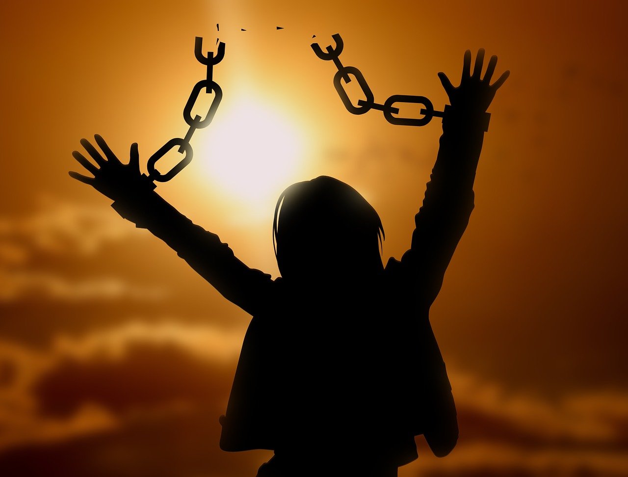 An image illustrating a person breaking free from chains of negative self-talk, symbolizing empowerment and self-confidence.